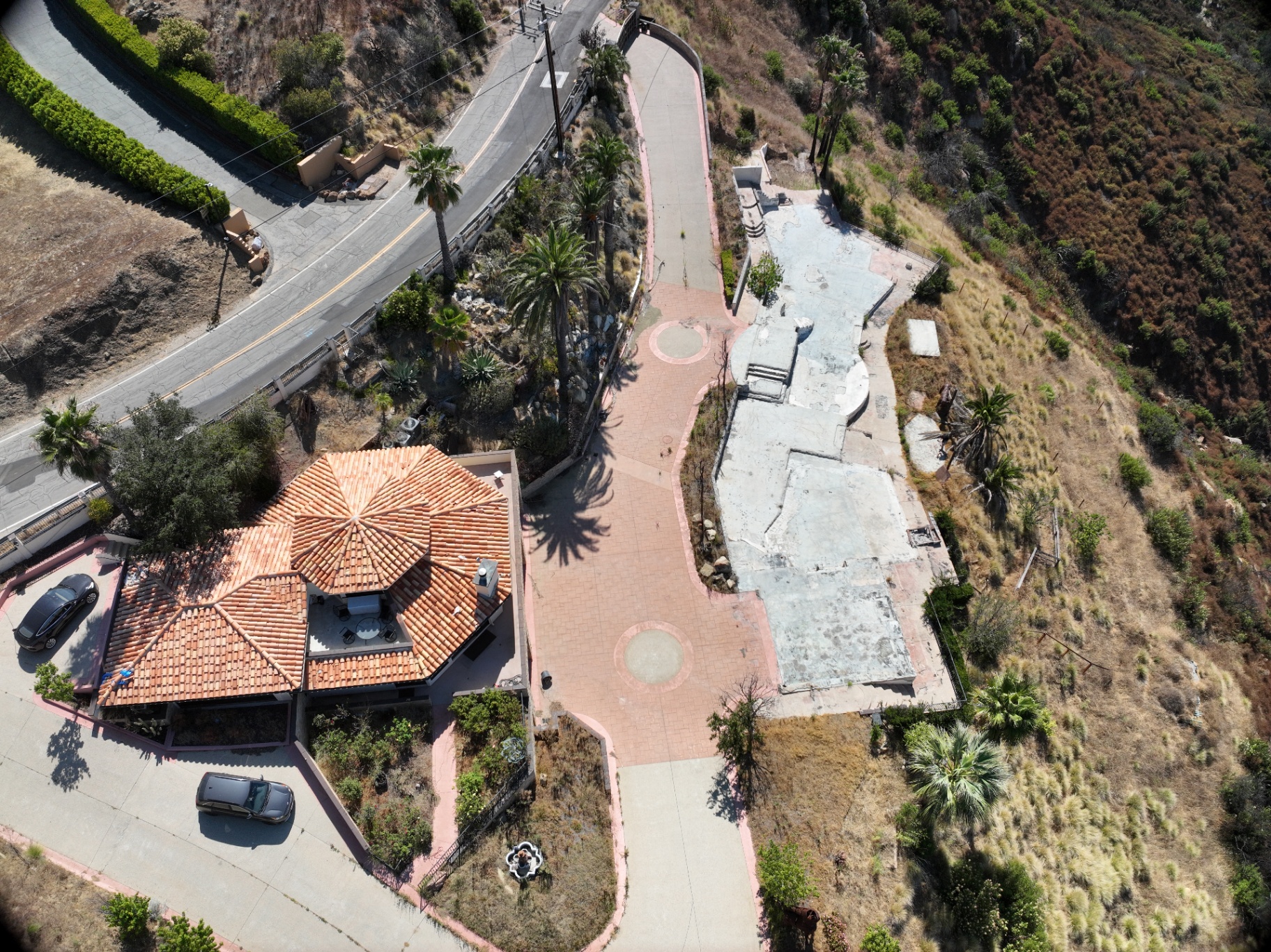 Aerial drone photograph of a Los Angeles hillside home next to a burned foundation slab